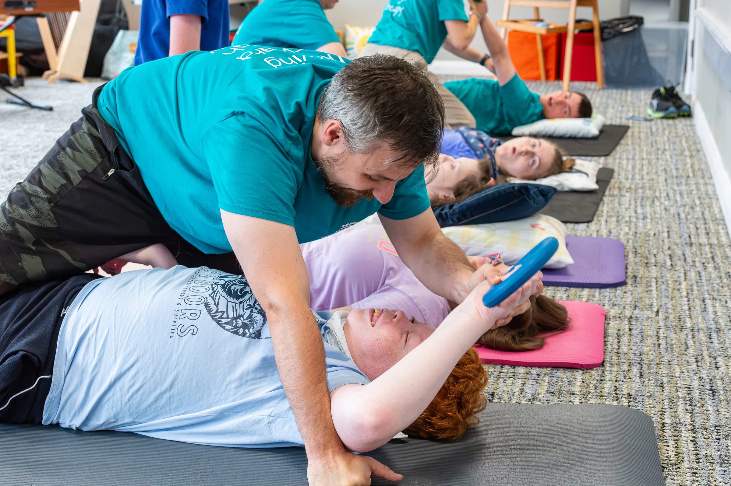 A therapist leaning in to support a young person through an arm stretch