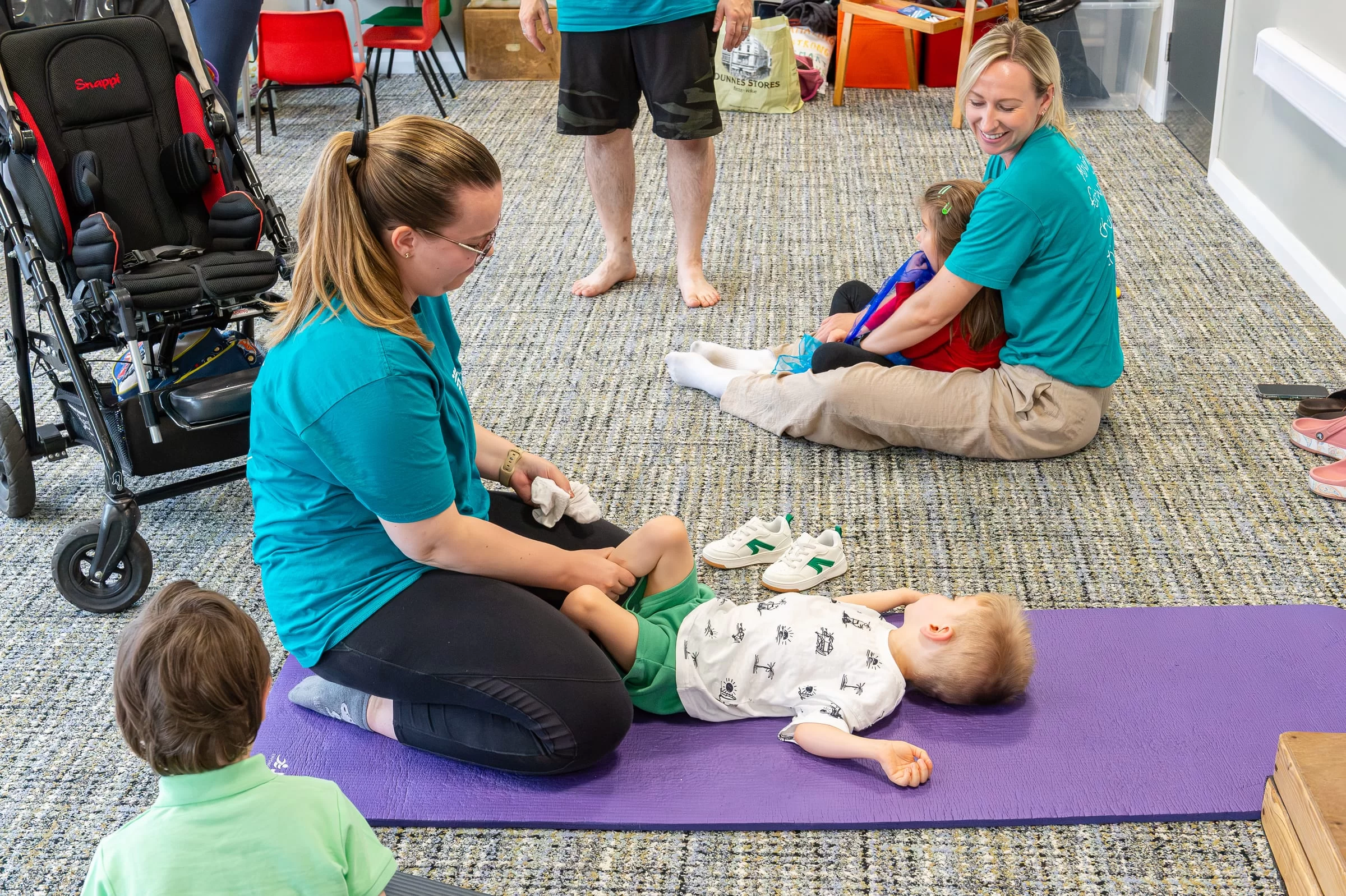 A therapist working gently with a baby lying on a padded floor mat
