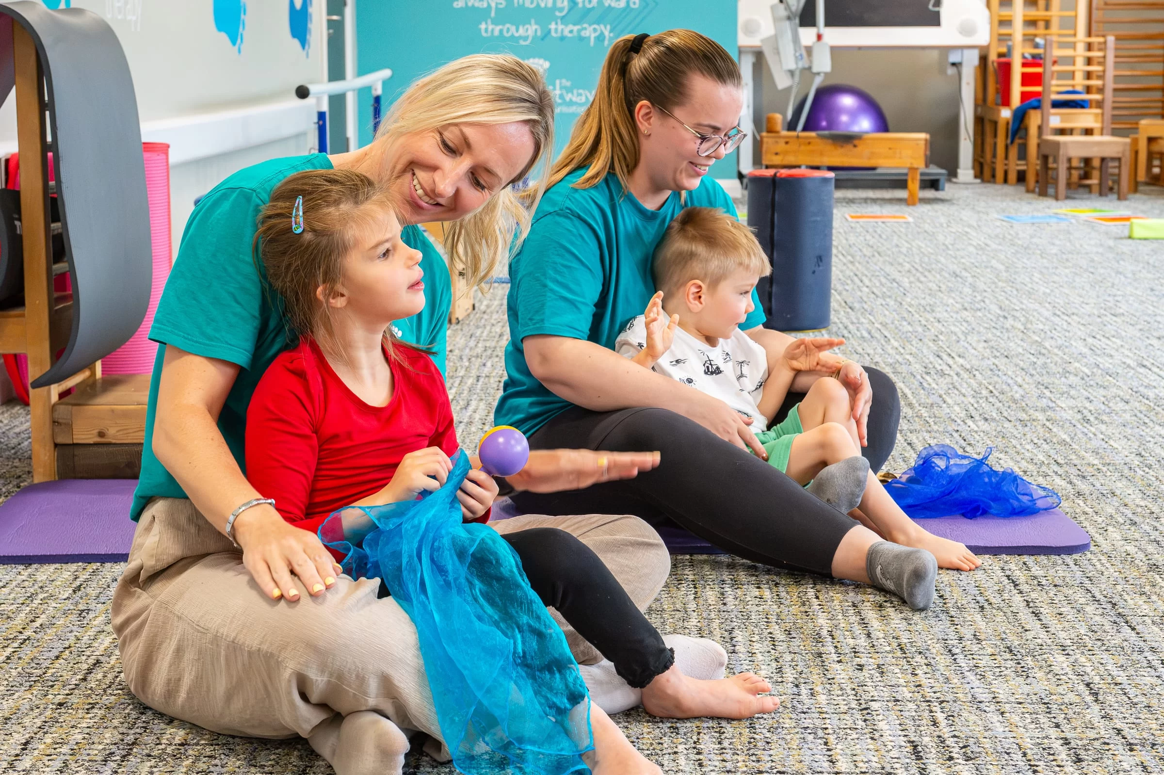 A seated group session with therapists and children working alongside one another