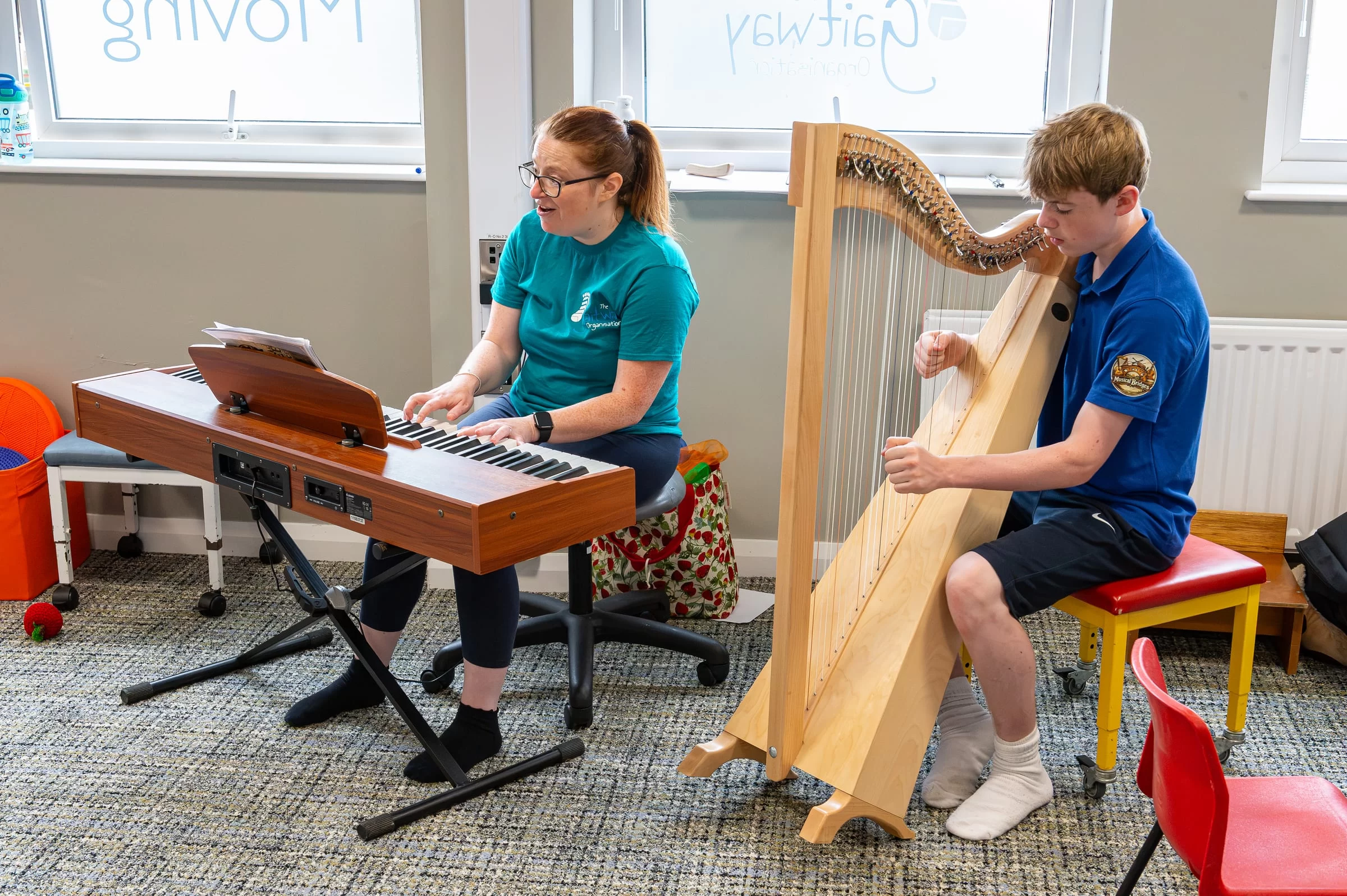 A music therapy session with a harp and an electric keyboard being played in the therapy room
