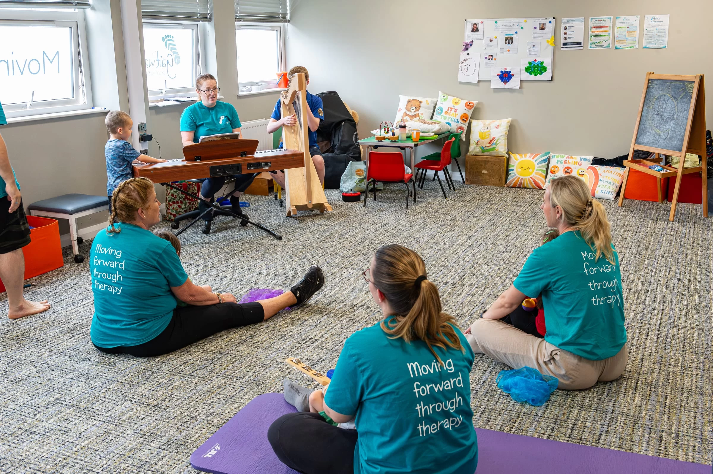 Therapists and children seated on the floor while live music is played nearby