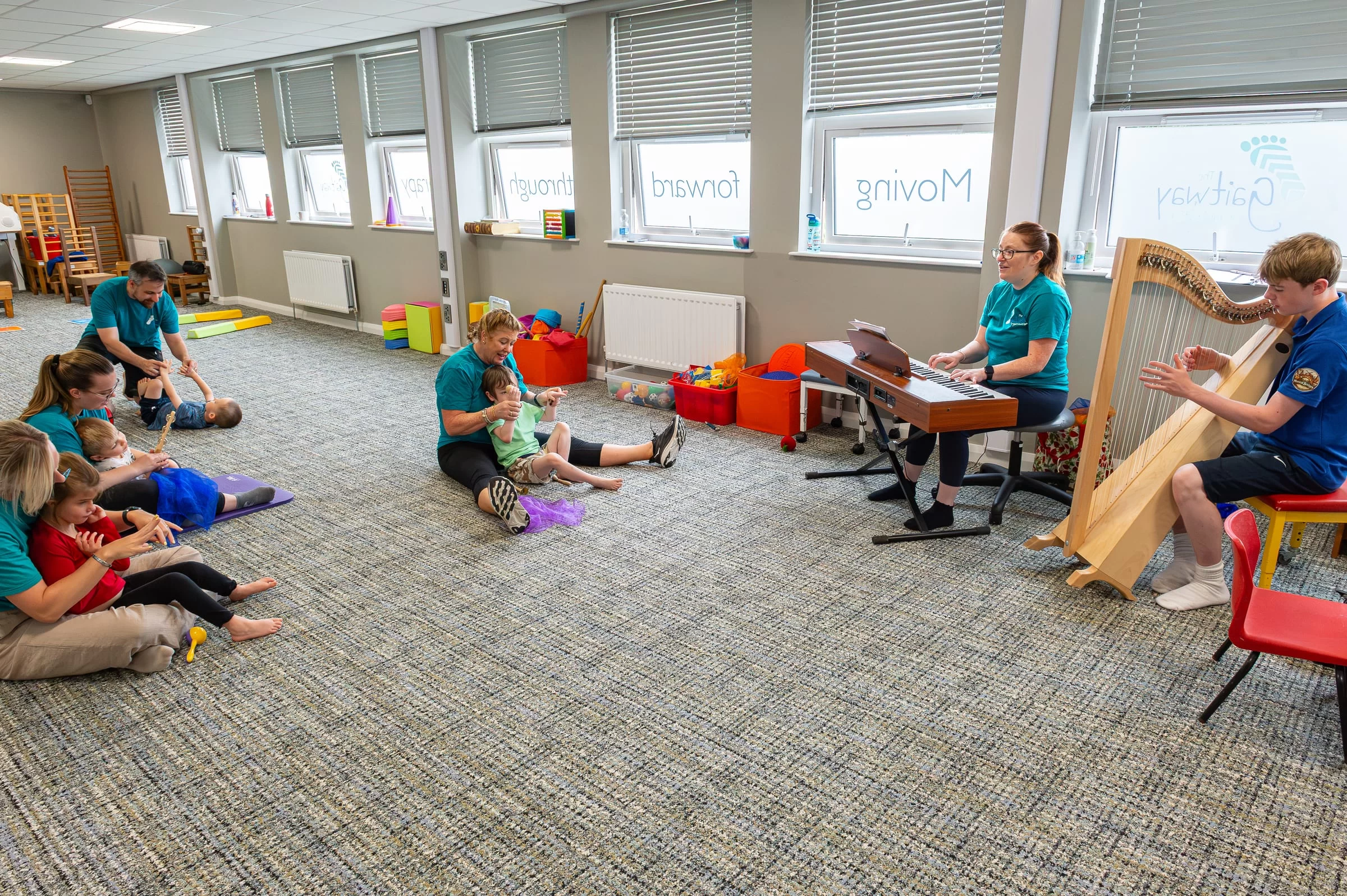A music therapy session with a harp and an electric keyboard being played in the therapy room