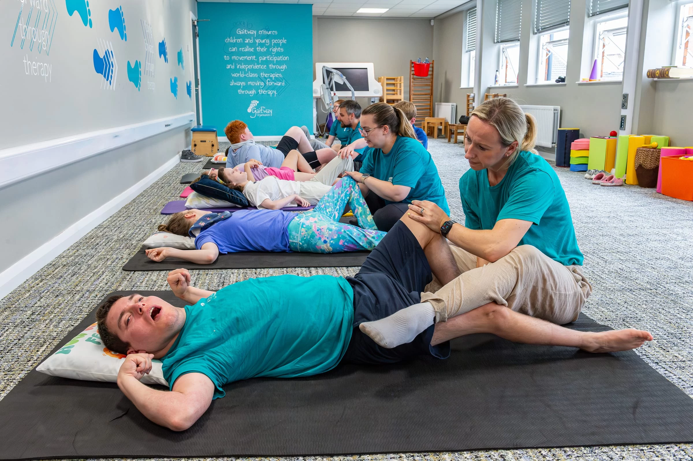 A wide view of the therapy room with several therapists and young people working in parallel
