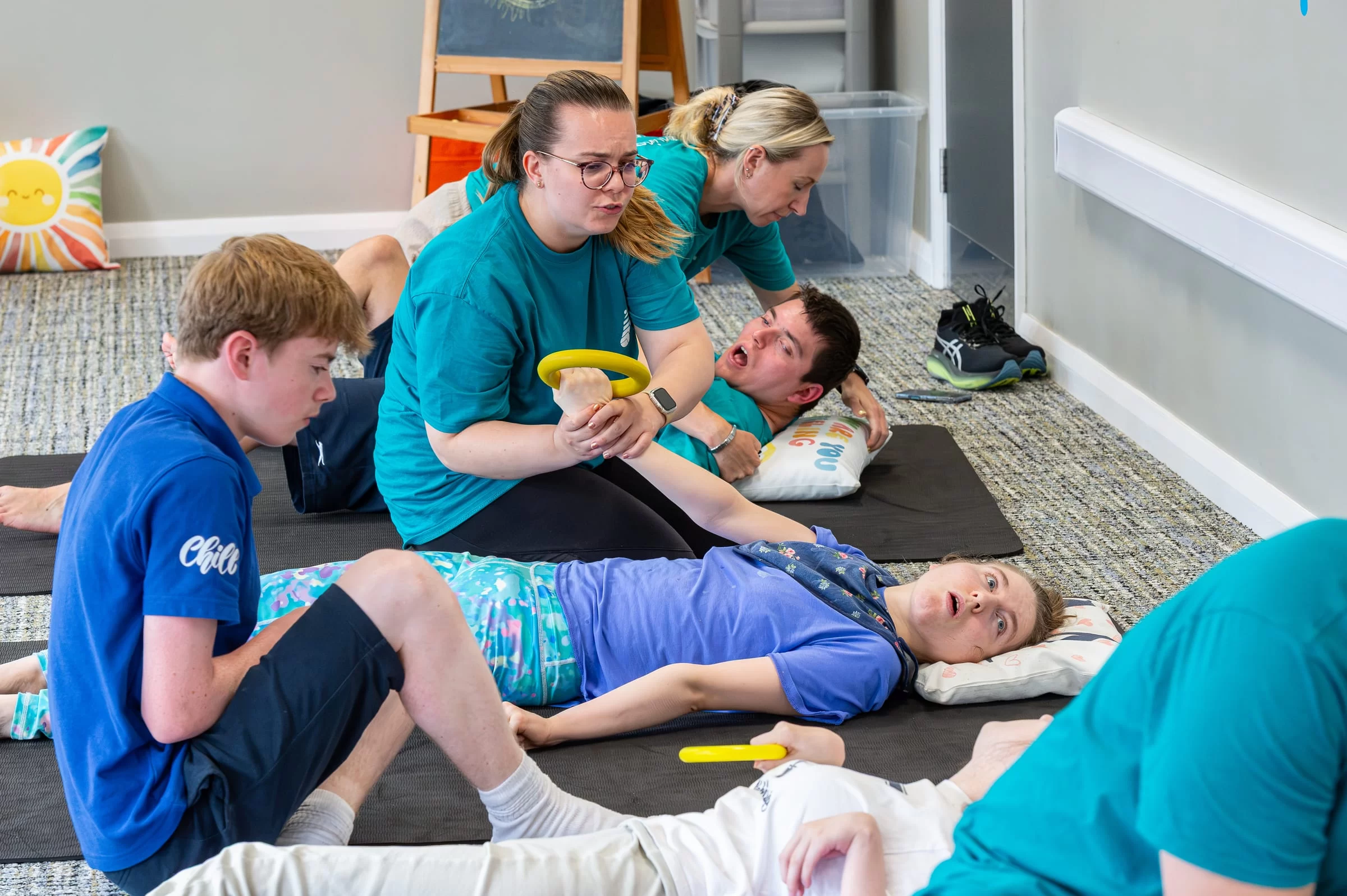 Two therapists working alongside one another with young people on adjacent mats