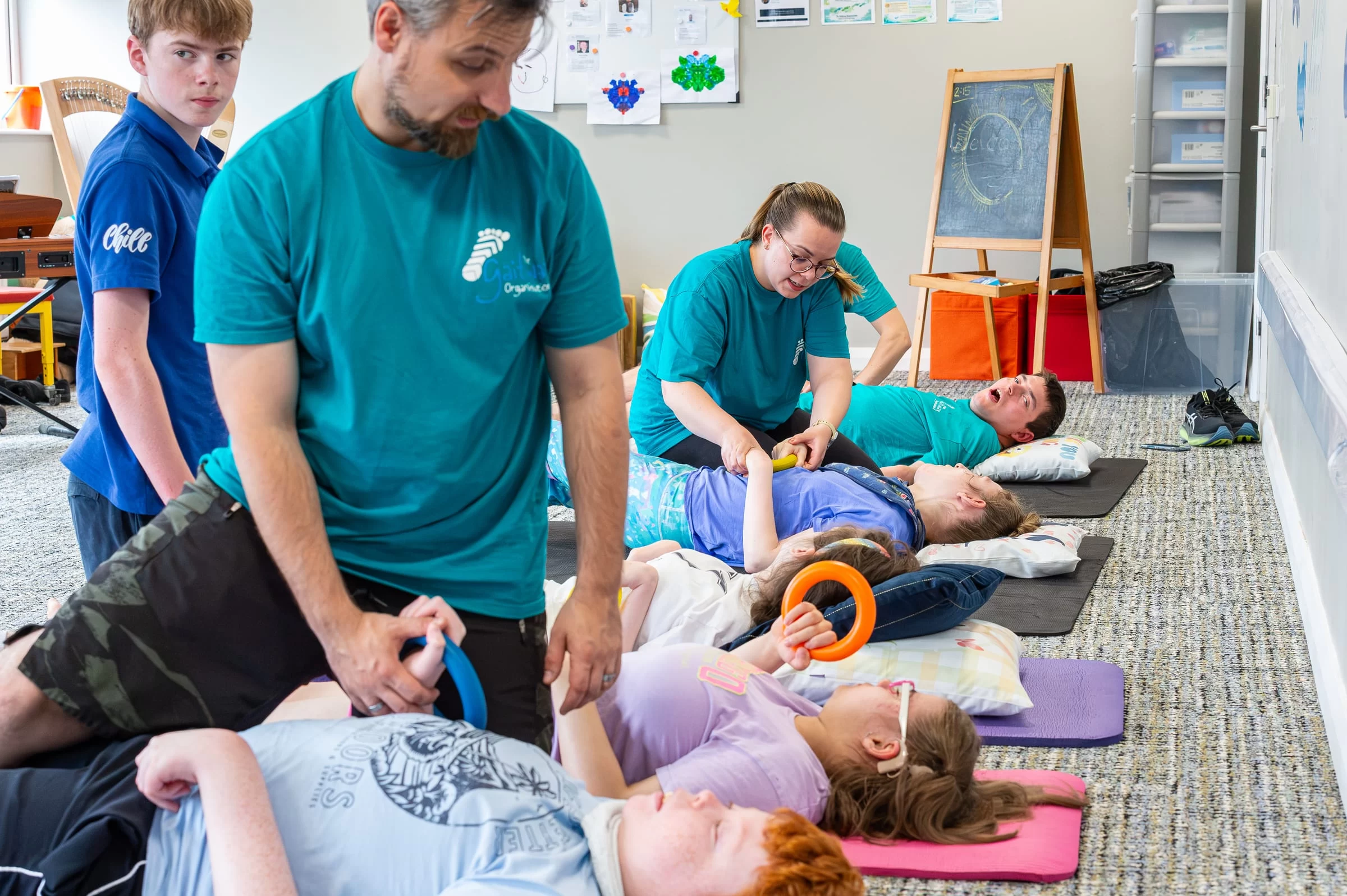 A therapist standing over a mat, steadying a young person through an exercise