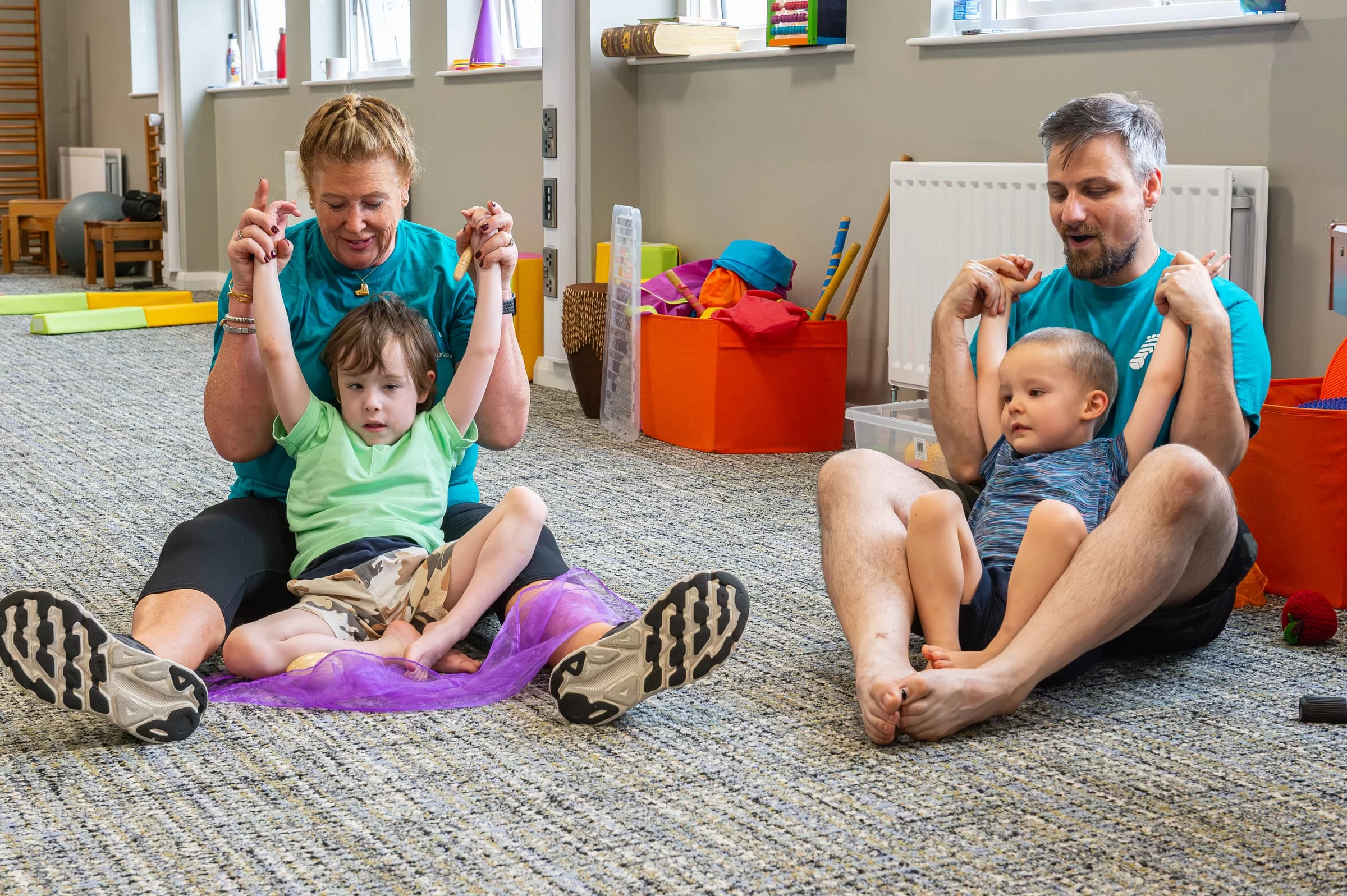 A therapist supporting a child's arms above their head during a stretching exercise