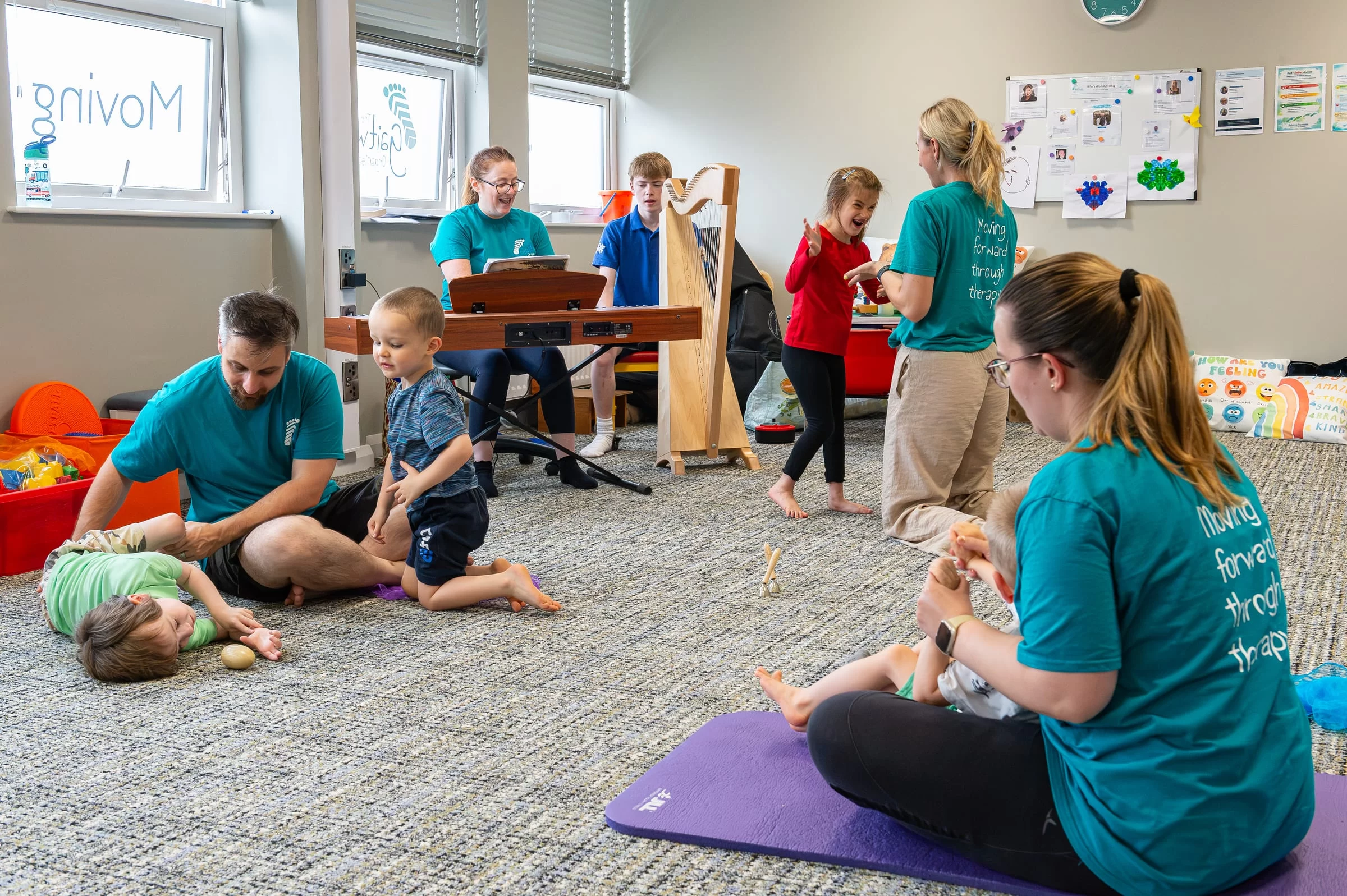 A therapy session under way on the floor, with a therapist and child working together and music being played in the background