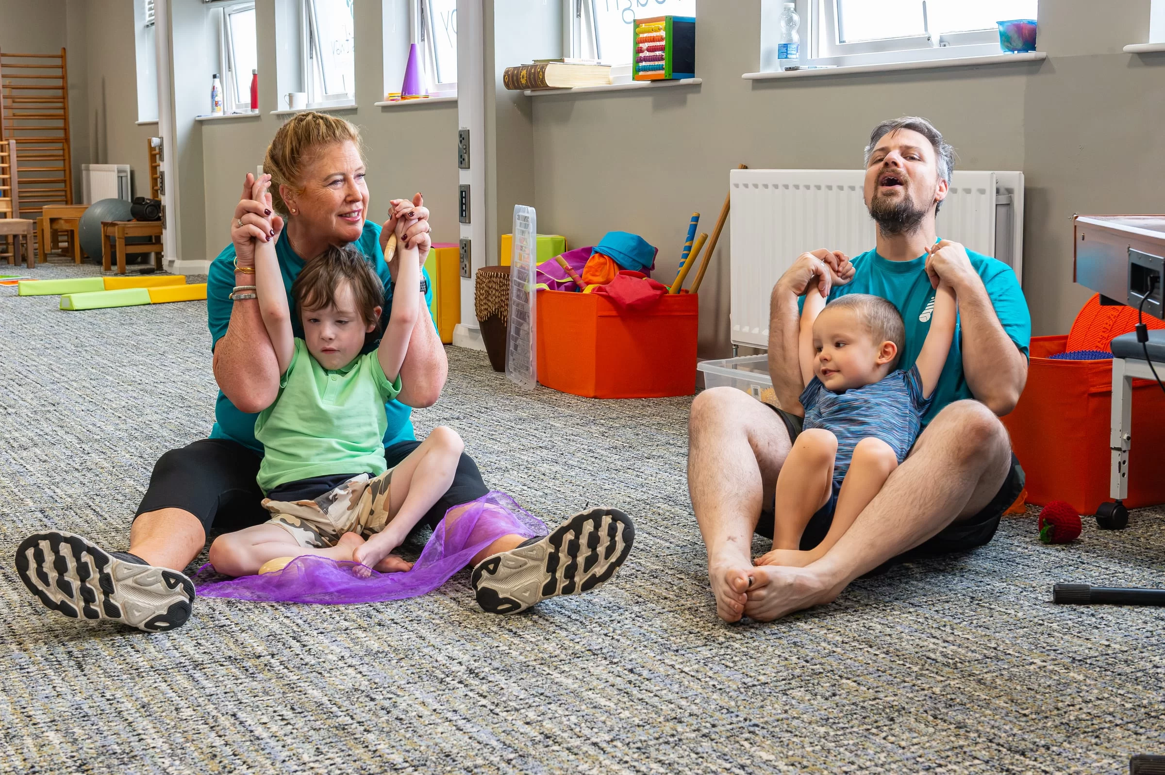 A therapist supporting a child to raise both arms overhead during a movement exercise