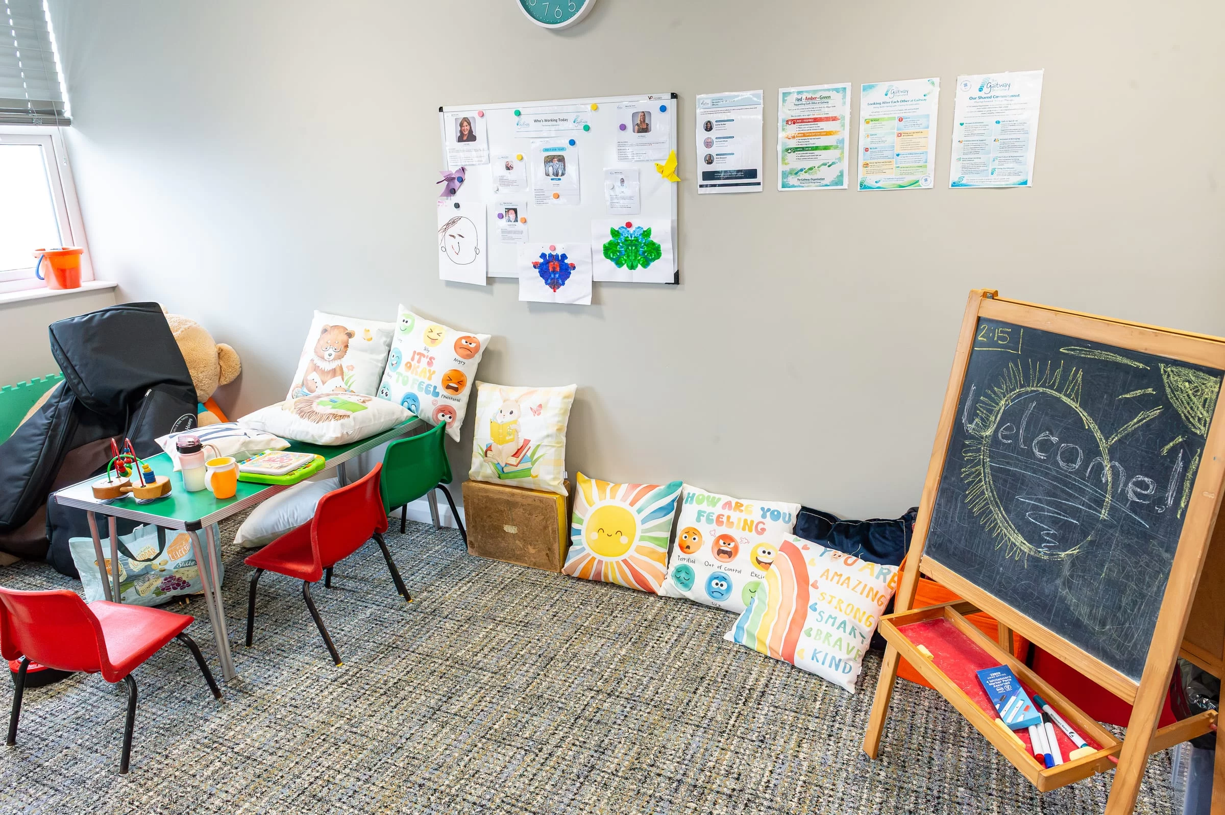 A quiet corner of the therapy room with a welcome board, picture books and small chairs