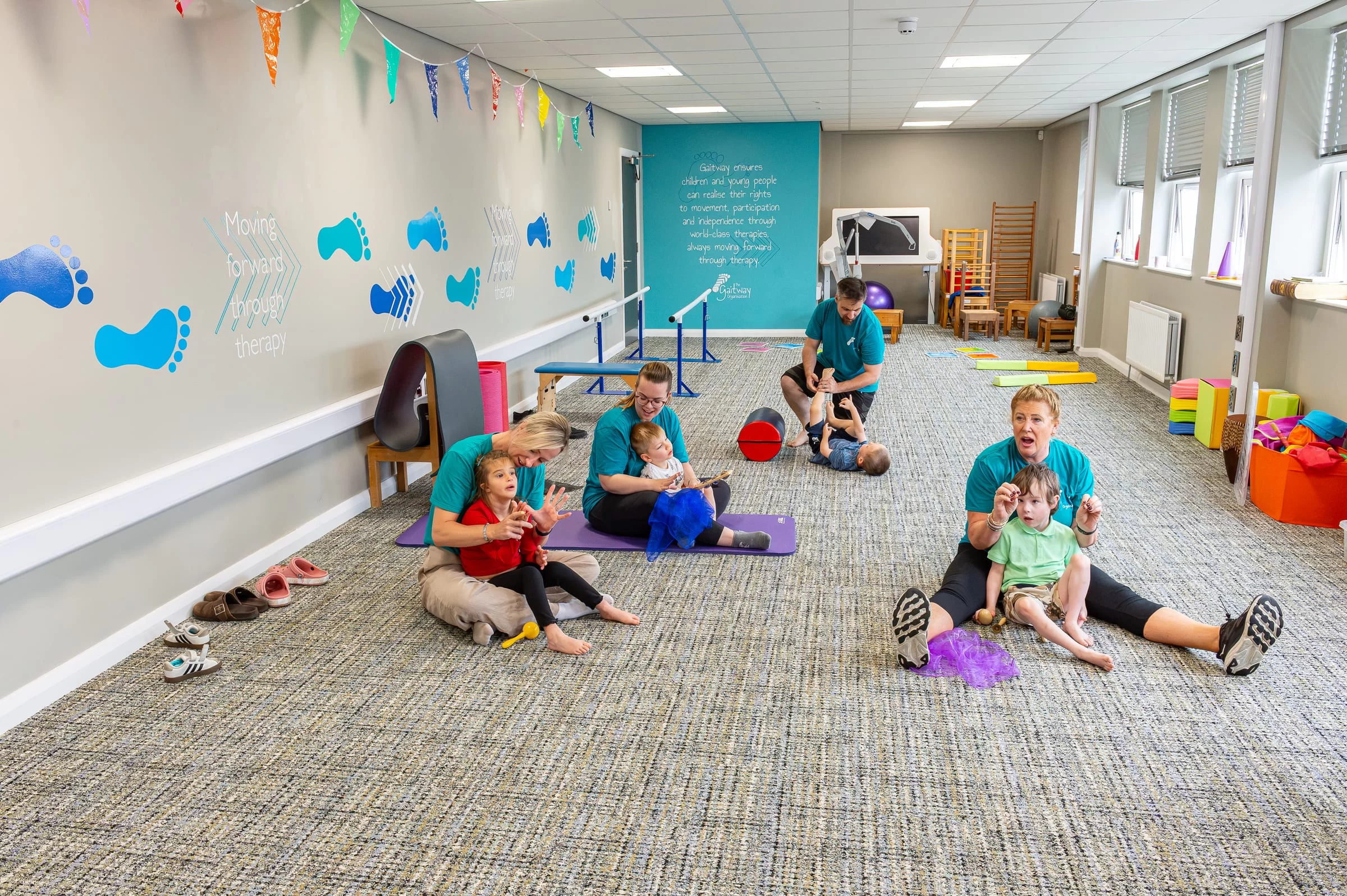 A wide view of the Gaitway therapy room with a session in progress across the floor