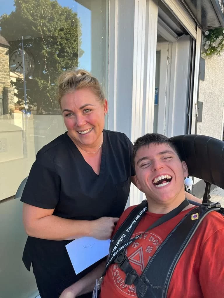 A member of staff at a supporting business smiling beside a young person who has just delivered a thank you card