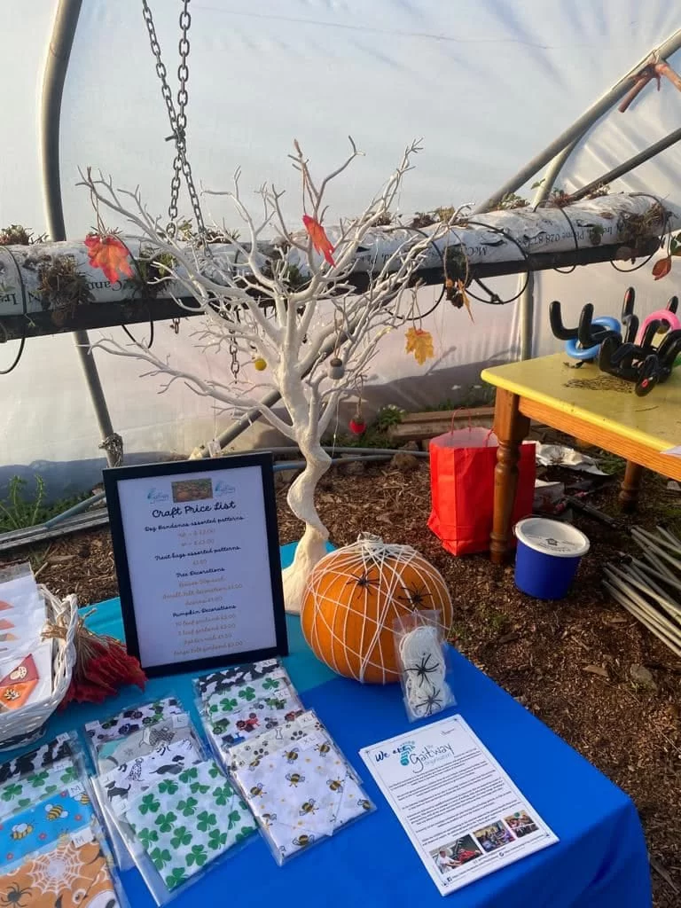 A white decorated tree, a pumpkin wrapped in a string spider's web and the craft price list on the Gaitway stall